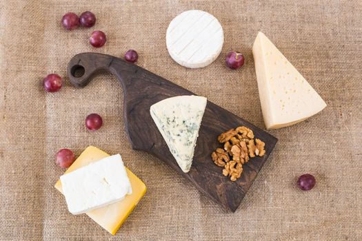 Various types of cheese, blue cheese and brie with grapes and nuts.