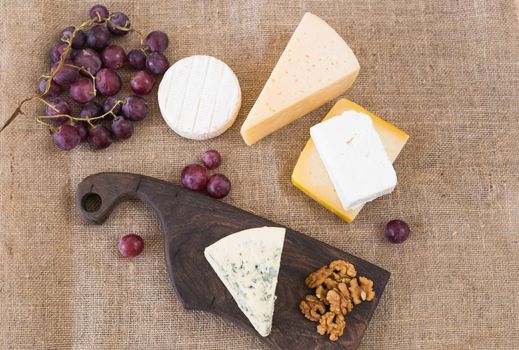 Cheese party table, perfect holiday appetizer with nut on rustic wooden board.