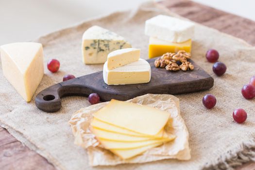 Fresh products. Cheese, brie, Camembert, grapes and nuts on rustic table