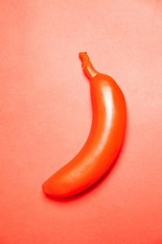 Top view of ripe whole banana painted in red color and placed on bright background
