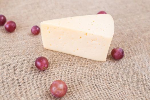 Piece of homemade cheese and grapes, top view.