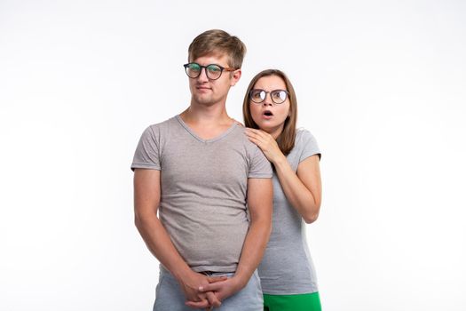 Education, people concept - a couple of young people in glasses look like they are nerds standing over the white background. Girl is afraid of something.