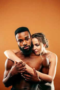 Young pretty couple diverse races together posing sensitive on brown background, lifestyle people concept close up