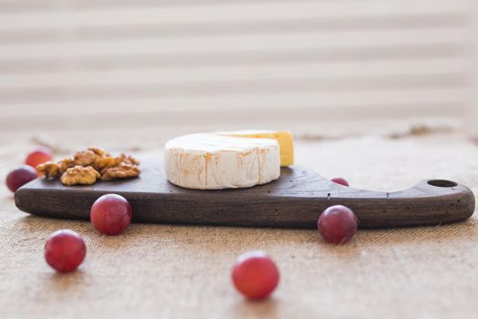 Brie or camembert cheese with figs, grapes and honey on wood