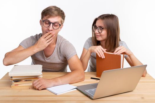 Education, people concept- a couple of young people in glasses look like they are bored of learning homework.