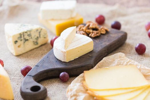 Fresh products. Cheese, brie, Camembert, grapes and nuts on rustic table