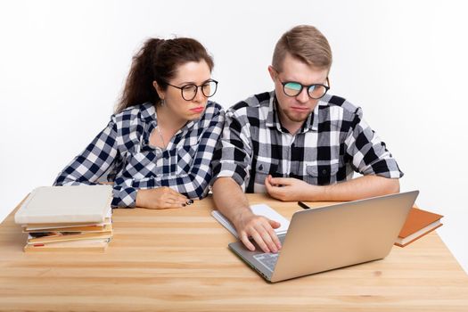 People and education concept - Two puzzled students in plaid shirts sitting at table.
