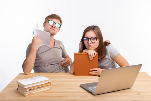 Education, people concept- a couple of young people in glasses look like they are bored of learning homework.