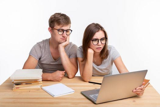 Education, people concept- a couple of young people in glasses look like they are bored of learning homework.