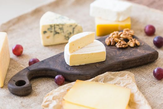 Cheese party table, perfect holiday appetizer with nut on rustic wooden board.