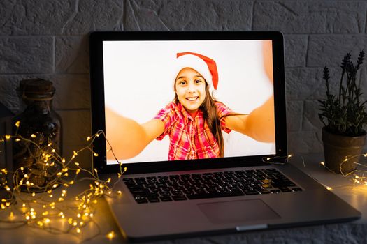 Child in christmas hat with tablet pc. Happy girl showing tablet screen.