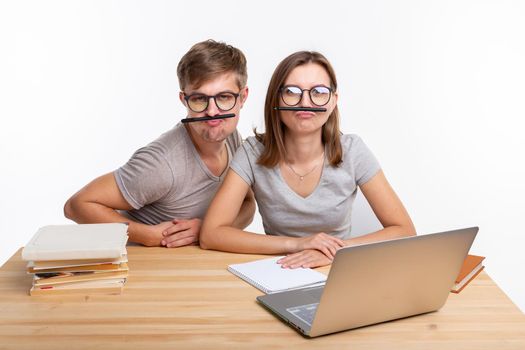 Education and people concept - a couple of young students in glasses look like they are bored of learning homework and make a stupid jokes.