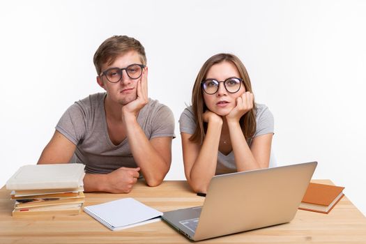 Education, people concept- a couple of young people in glasses look like they are bored of learning homework.