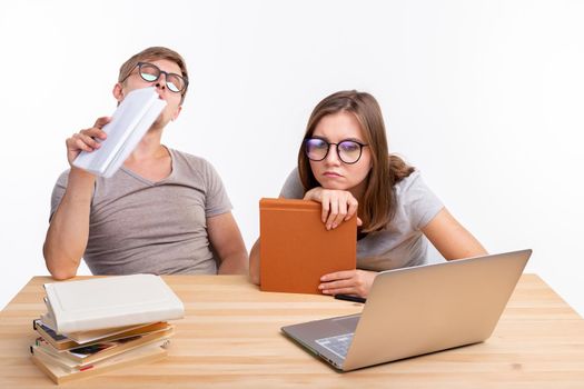 Education, people concept- a couple of young people in glasses look like they are bored of learning homework.