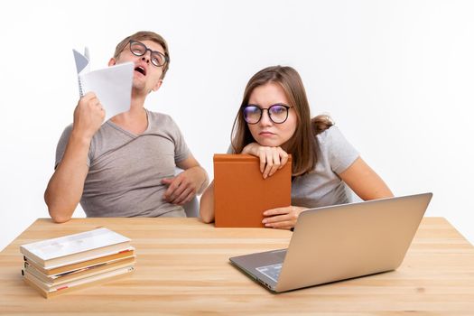 Education, people concept- a couple of young people in glasses look like they are bored of learning homework.