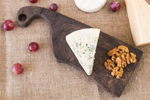 Cheese party table, perfect holiday appetizer with nut on rustic wooden board.