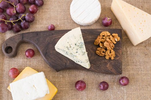 Cheese party table, perfect holiday appetizer with nut on rustic wooden board.