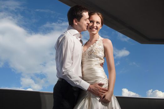 Happy bride and groom at the wedding walk in front of blue sky in city