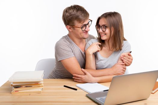 Education, people and relationship concept - a couple of students is hugging, because they are tired of doing homework.