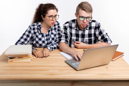 People and education concept - Two puzzled students in plaid shirts sitting at table.