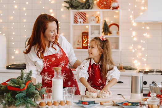 Mom and daughter in the New Year's kitchen together prepare dough for Christmas cookies.