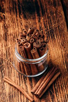 Cinnamon sticks in a glass jar over rustic wooden surface