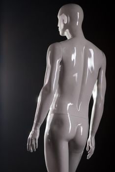 Rear view of male fashion mannequin against a black background