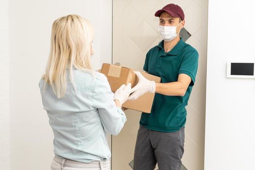 Woman and courier during order transfer. Woman accepting delivery from deliveryman. Cropped image of delivery service worker giving parcel to client.