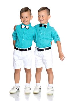 Two cute little boys stand in front of the camera in full growth. The concept of a happy childhood, the development of a child in the family. Isolated on white background.