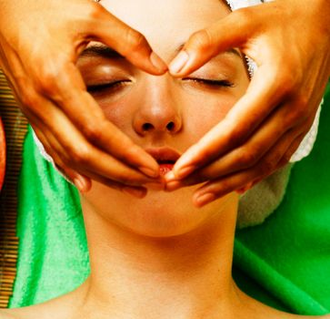 Attractive lady getting spa treatment in salon, closeup asian tan hands on face