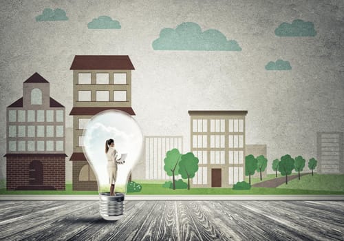 Businesswoman inside light bulb against city drawn concept
