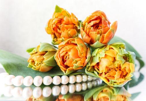 Beautiful orange tulips and white pearls on the mirror. Perfect for background greeting card