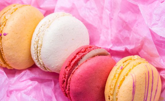 Colorful french cookies macarons set on pink background. Tasty fruit, almond sweet cookies, cake macaron. Holiday backdrop design.