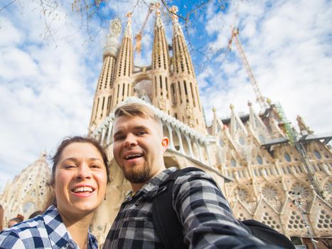 BARCELONA, SPAIN - FEBRUARY 6, 2018: Happy tourists photographing in front of the famous Sagrada Familia roman catholic church in Barcelona, architect Antoni Gaudi.