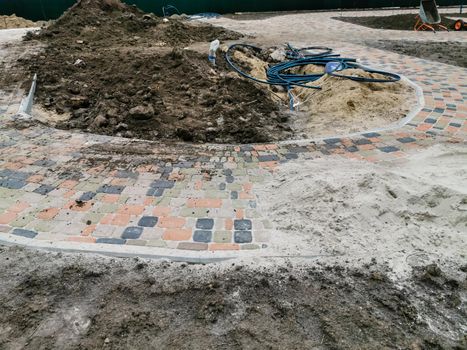 industrial worker installing pavement rocks, cobblestone blocks on road pavement