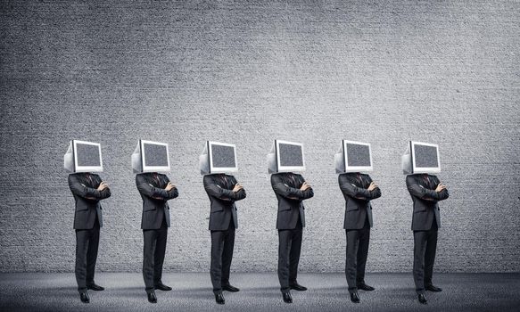 Businessmen in suits with monitors instead of their heads keeping arms crossed while standing in a row in empty