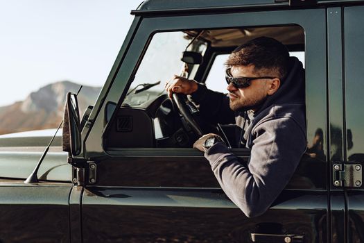 Male driver of an off-road car looking through the window while driving