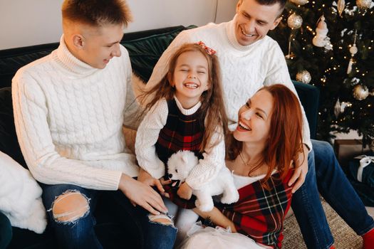 Close-up portrait of a happy family sitting on a sofa near a Christmas tree celebrating a holiday.