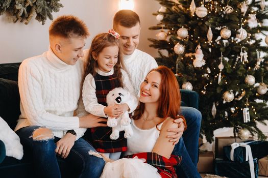 Close-up portrait of a happy family sitting on a sofa near a Christmas tree celebrating a holiday.