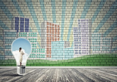 Businesswoman inside light bulb against city drawn concept