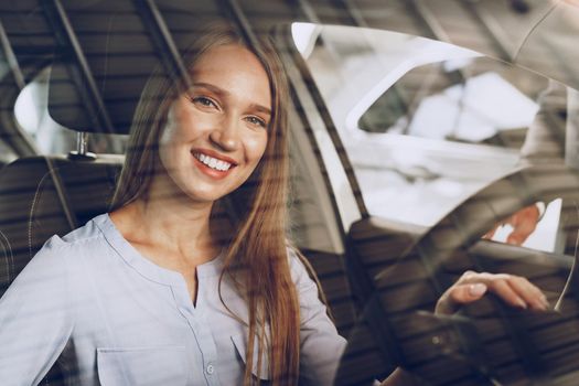 Attractive young woman sitting in new car in showroom close up