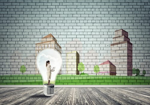 Businesswoman inside light bulb against city drawn concept