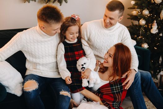 Close-up portrait of a happy family sitting on a sofa near a Christmas tree celebrating a holiday.