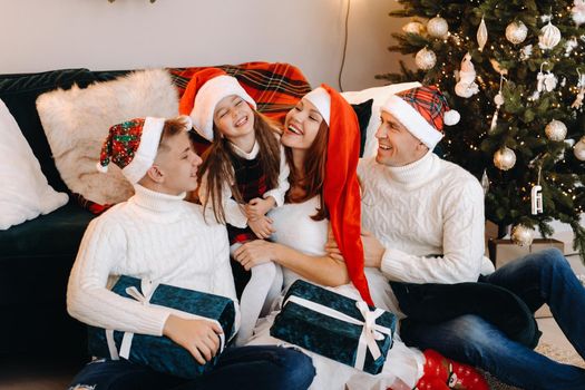 Close-up portrait of a happy family sitting on a sofa near a Christmas tree celebrating a holiday.