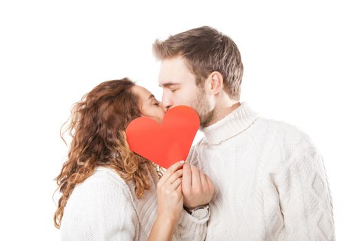 Happy couple kissing behind a red heart isolated on white background
