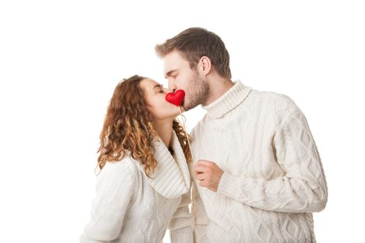 Happy couple kissing behind a red heart isolated on white background