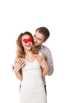 Portrait of joyful couple holding red hearts by their eyes and laughing