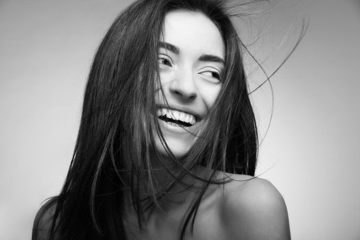 Portrait of attractive caucasian smiling woman with long hair on grey background.Looking at camera