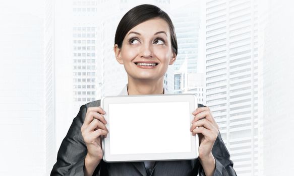 Businesswoman holding tablet computer with blank screen. Smiling woman in business suit show tablet PC and looking upward. Corporate businessperson on downtown background. Digital technology layout