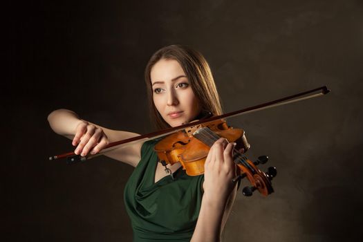 Beautiful young woman playing violin over black background